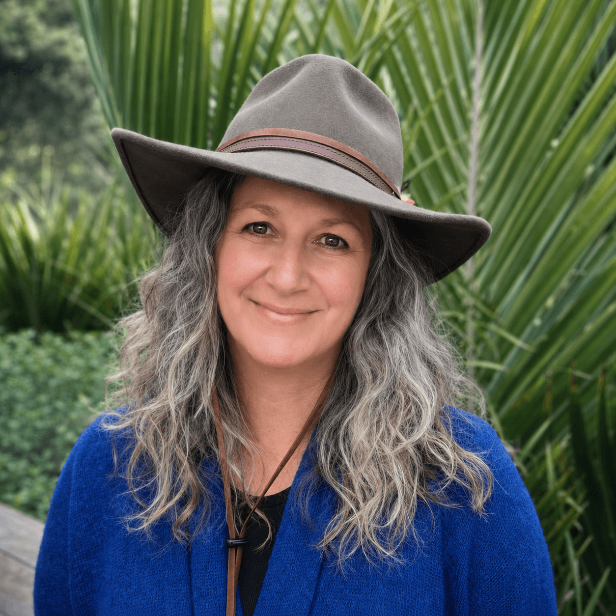 Larissa, The Soul Doctor, wearing a brown felt hat outdoors among native greenery